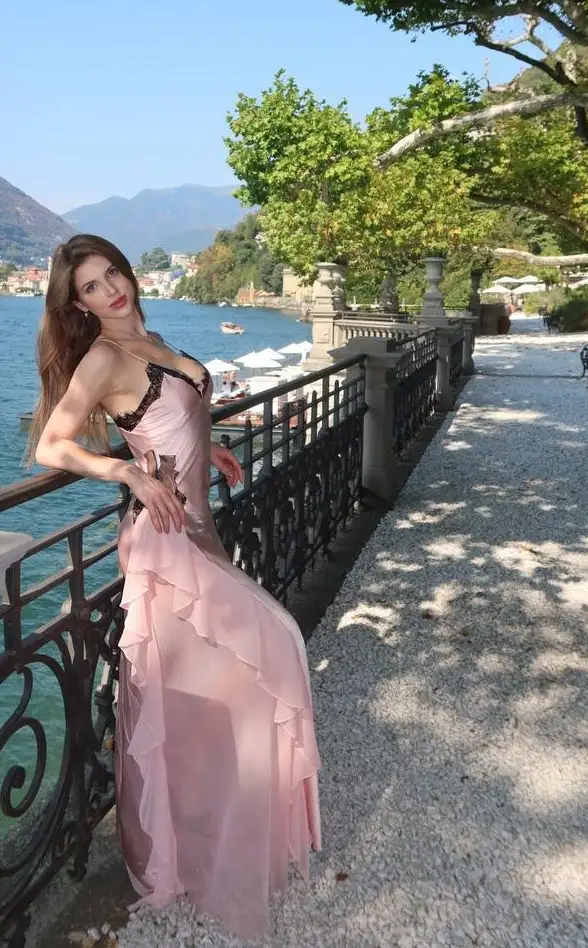 Woman in long pink dress posing by Lake Como.