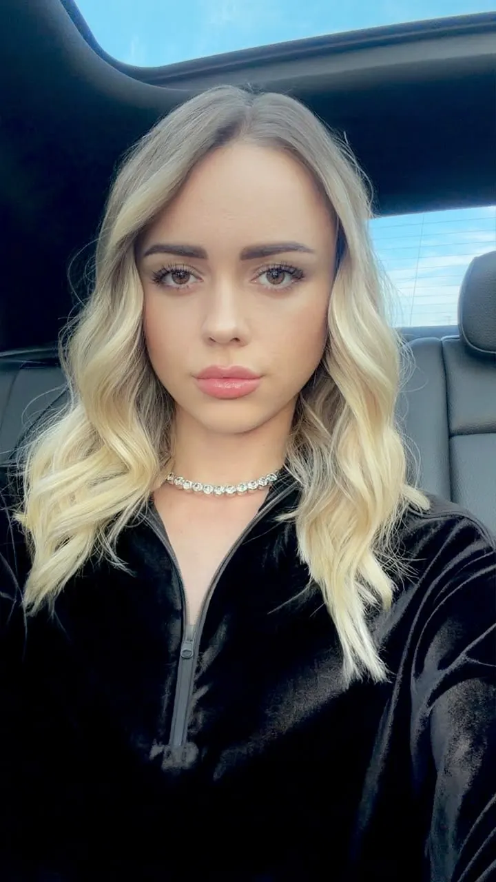 Blonde woman in a black velvet top and silver necklace.