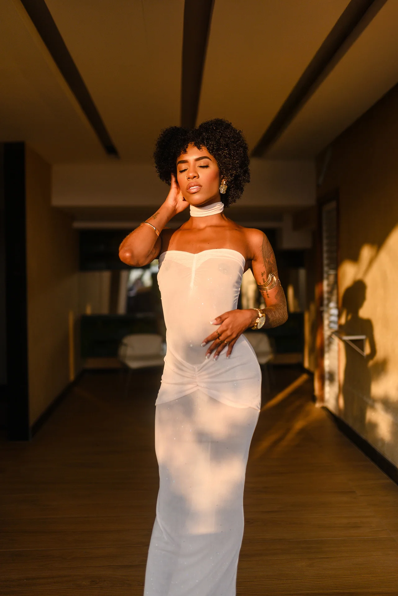 Woman with afro posing in white strapless gown indoors