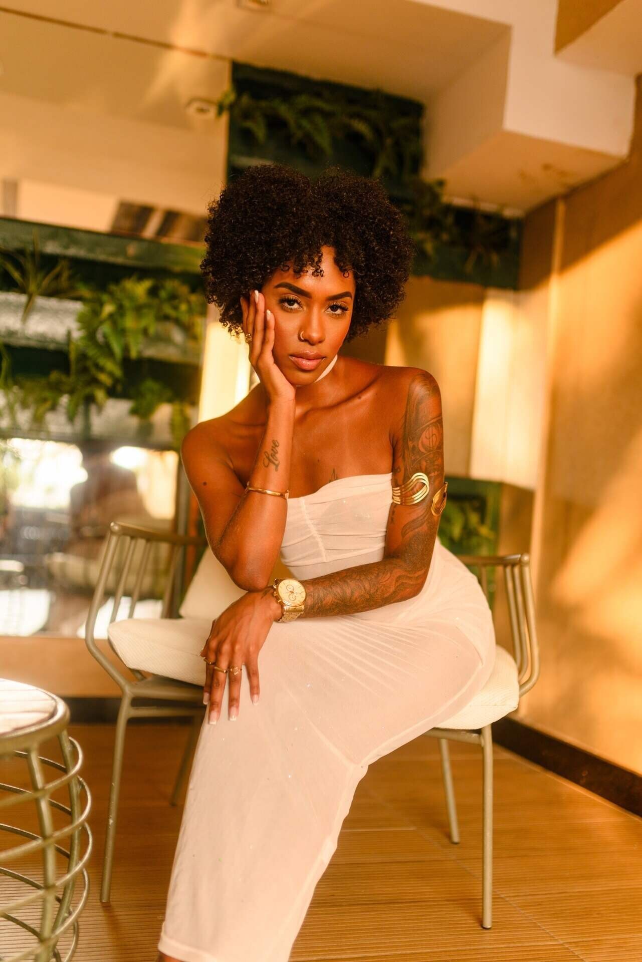 galene Stylish woman in white dress posing under warm lighting.