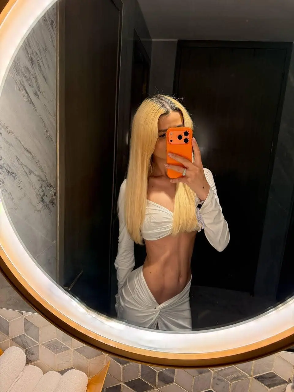 Mirror selfie of a blonde woman in a white outfit.