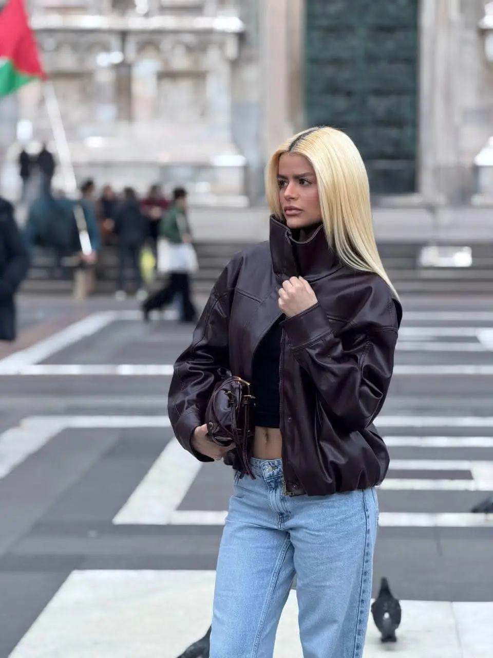 Blonde woman in brown leather jacket and blue jeans.