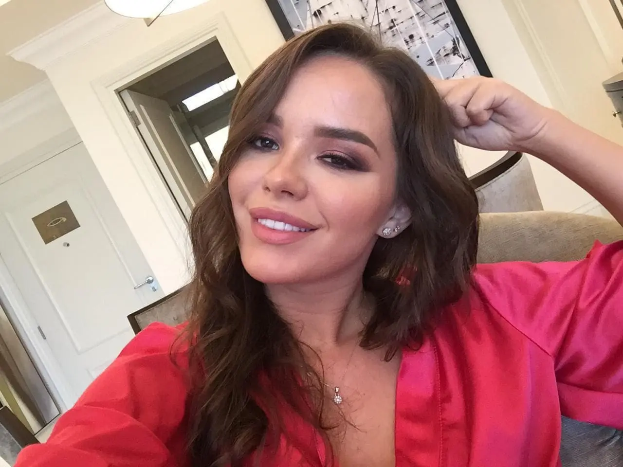 Smiling woman with brown hair wearing a pink silk robe.