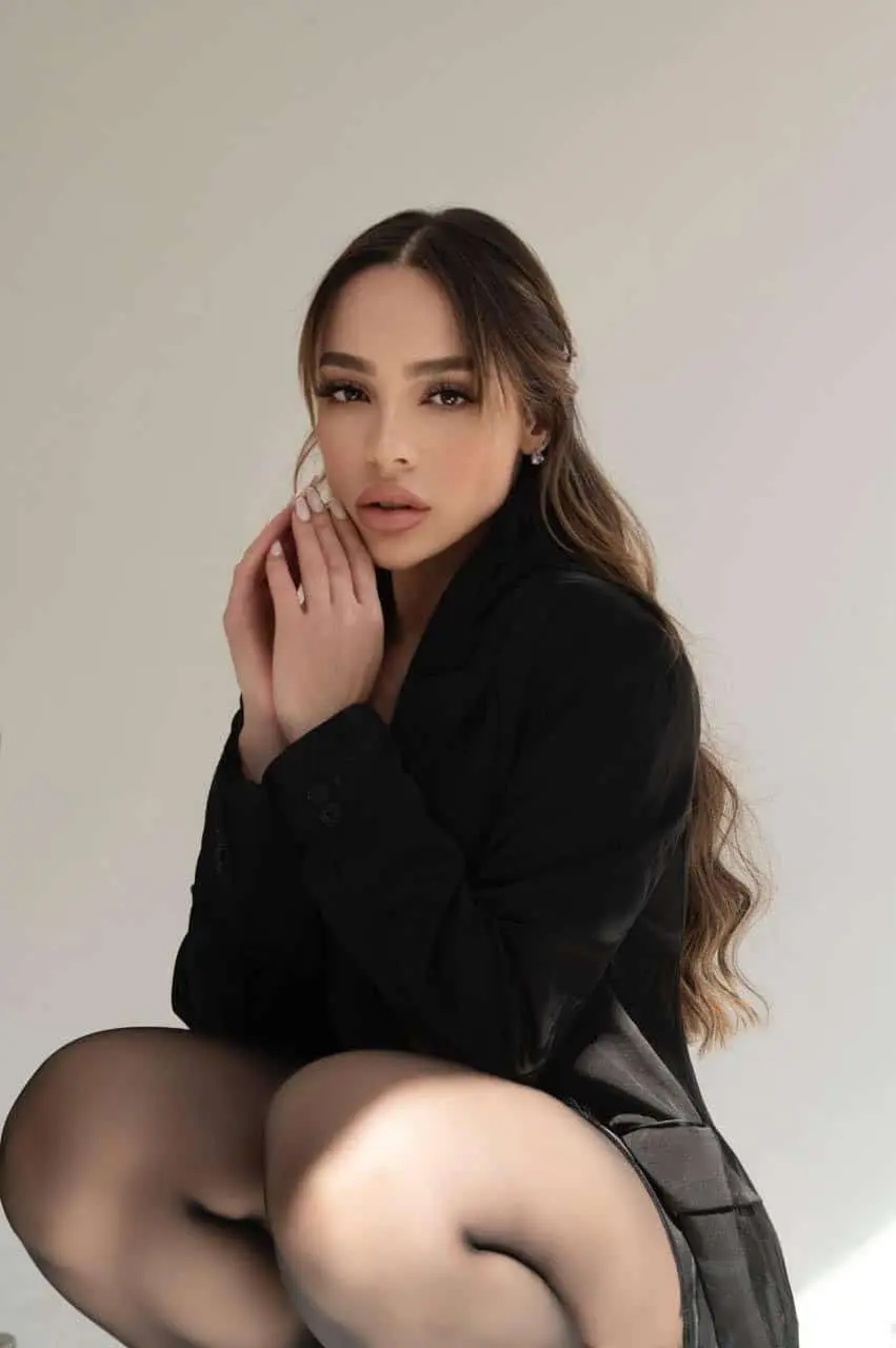 Woman in black jacket posing indoors.