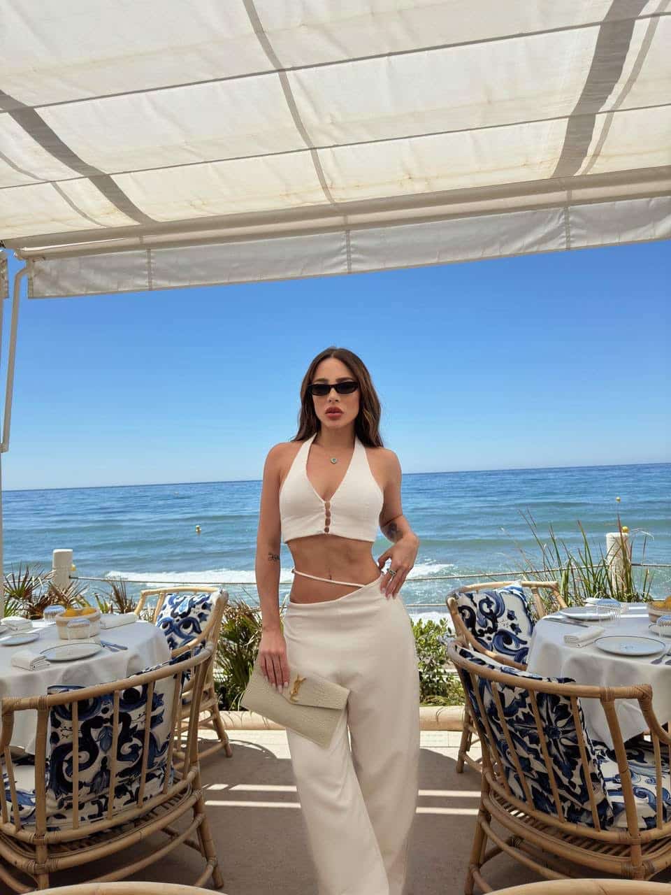 Woman in white outfit by seaside restaurant.