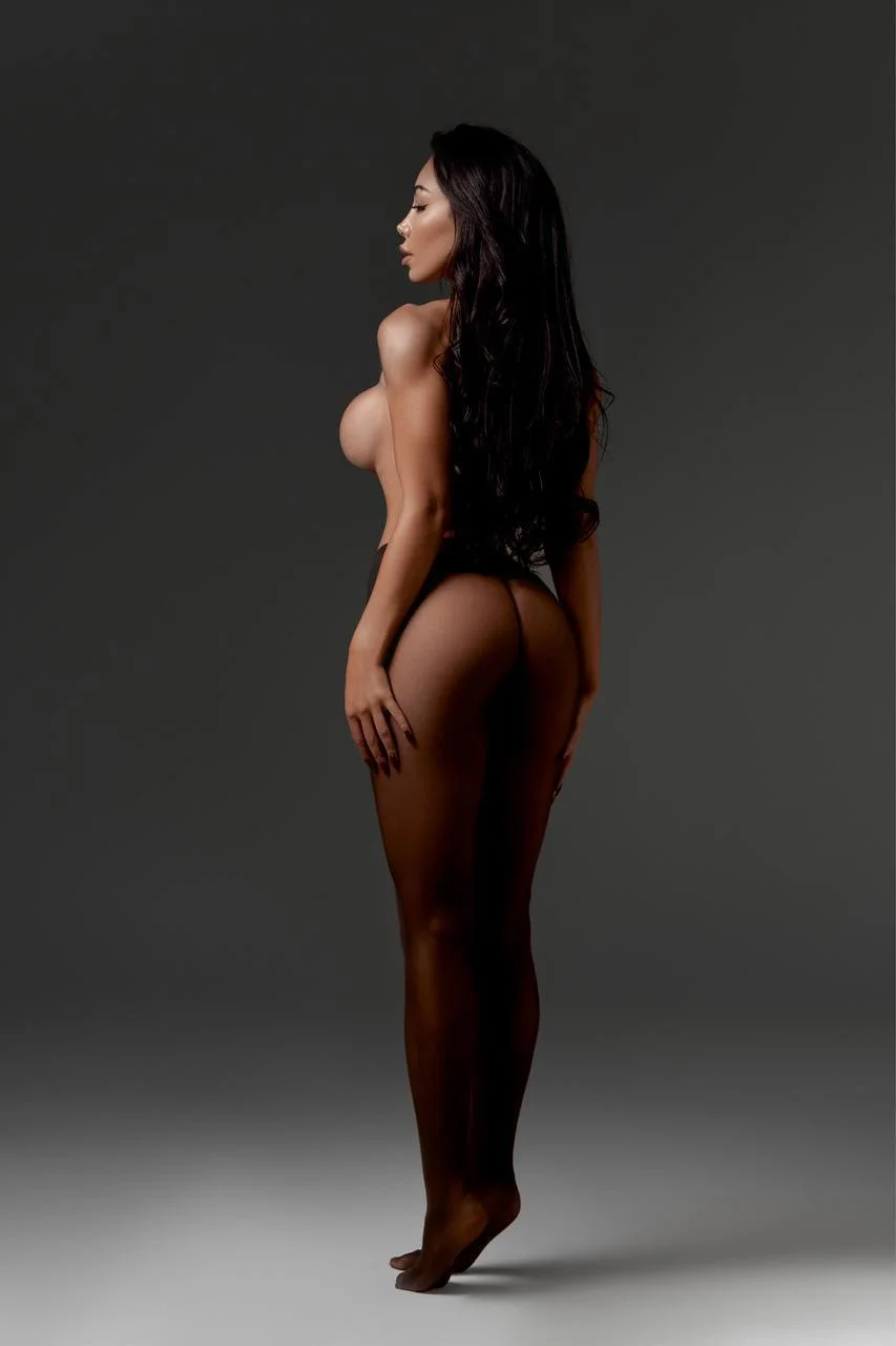 Woman with long dark hair posing in black tights.