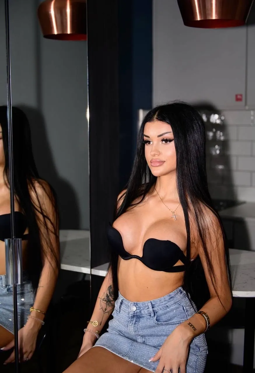 A woman in a black plunge bra and denim skirt