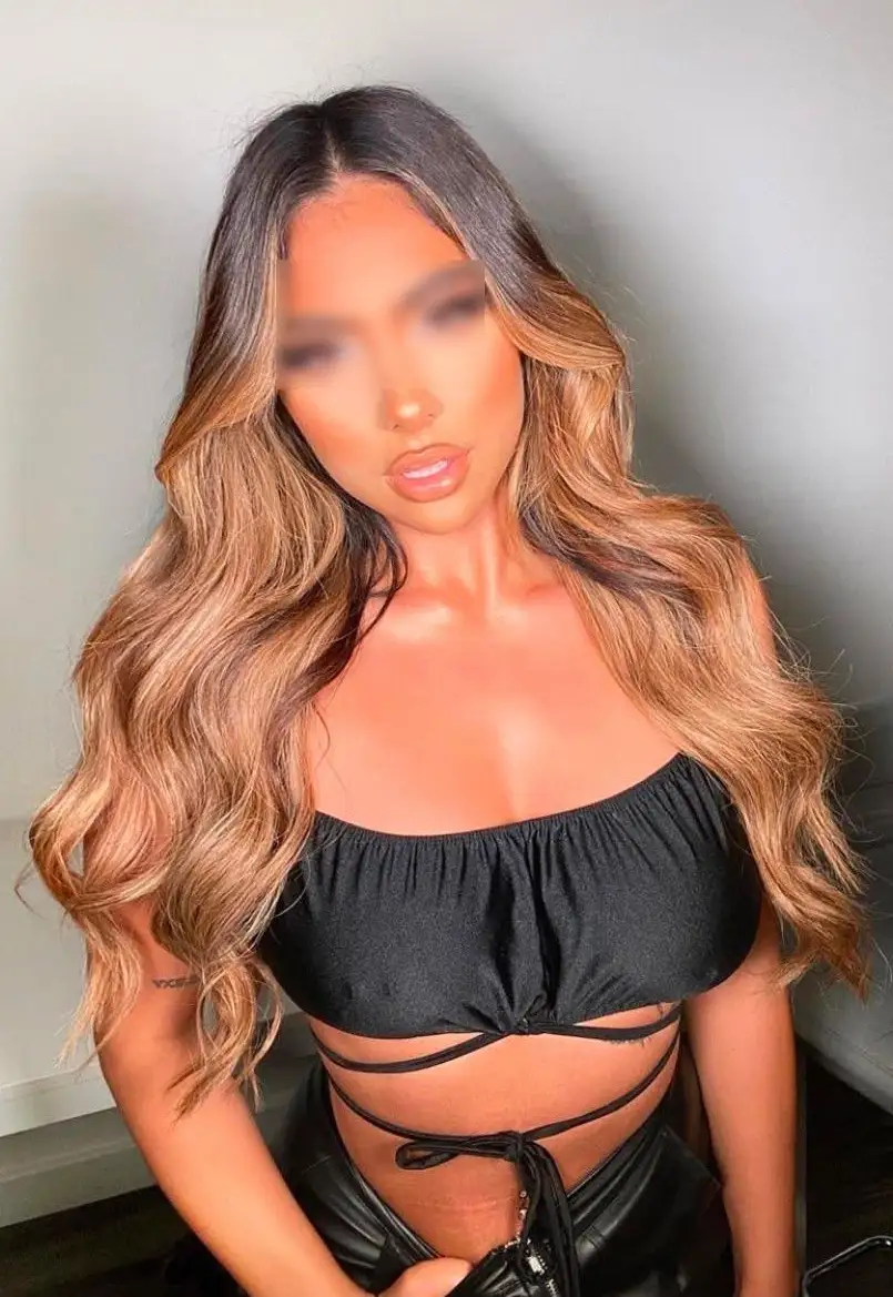 Woman with long wavy brown hair in black crop top.