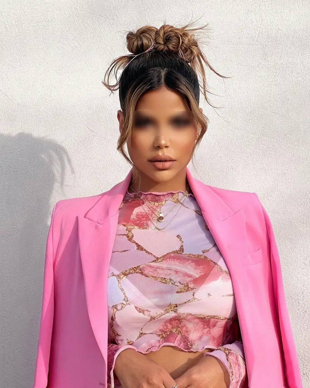 Woman in a pink blazer with a high bun hairstyle