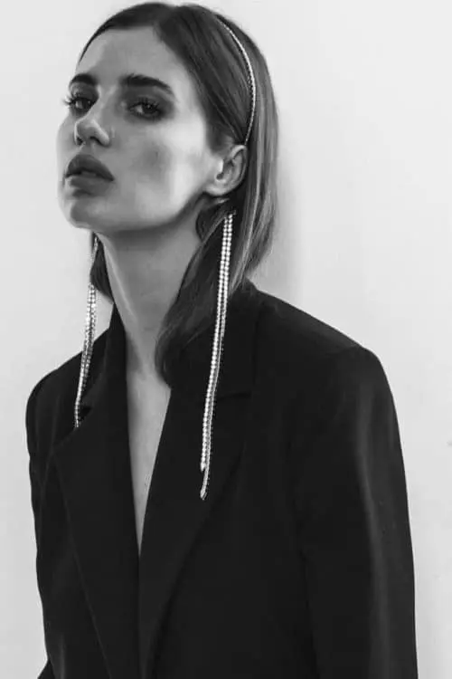 Woman in black blazer with long earrings.