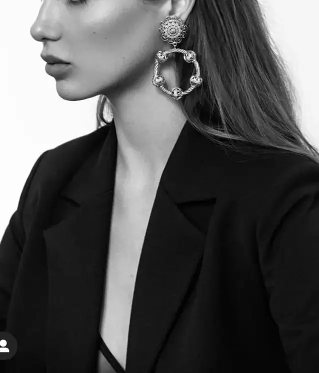 Woman in black blazer with large earrings