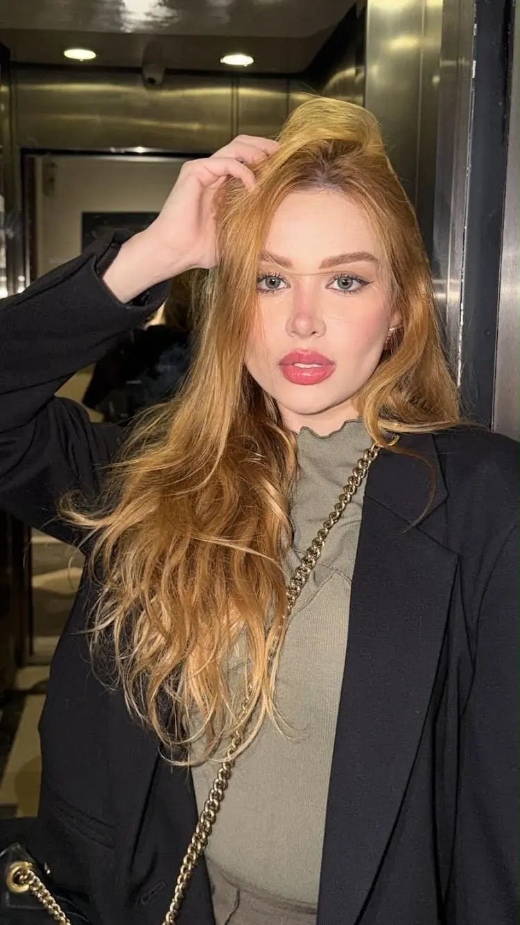 Stylish woman with long ginger hair posing in a blazer.