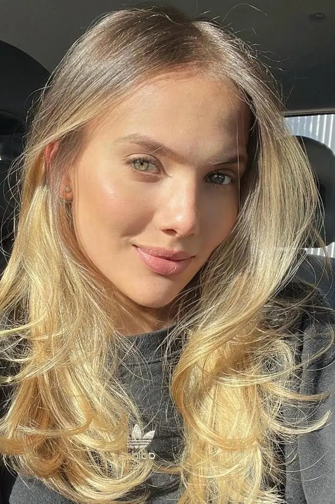 A blonde woman with green eyes in a car.