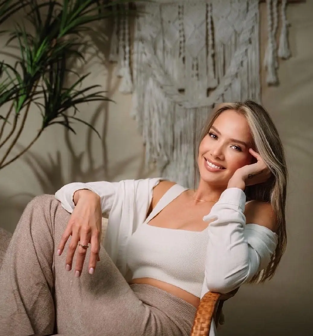 Woman with blonde hair smiling in a bohemian-style room.