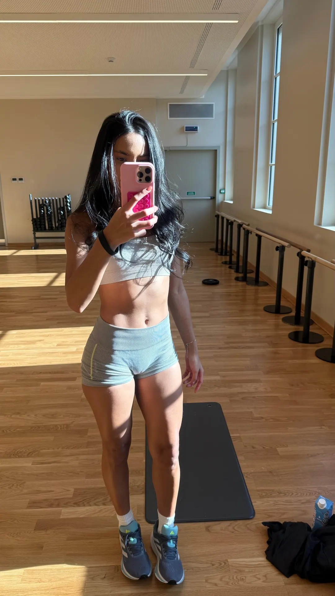 Woman in sportswear taking a mirror selfie in a gym.