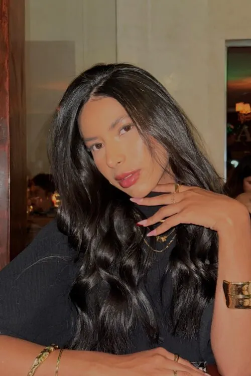 A glamorous woman with long dark hair wearing gold jewellery.