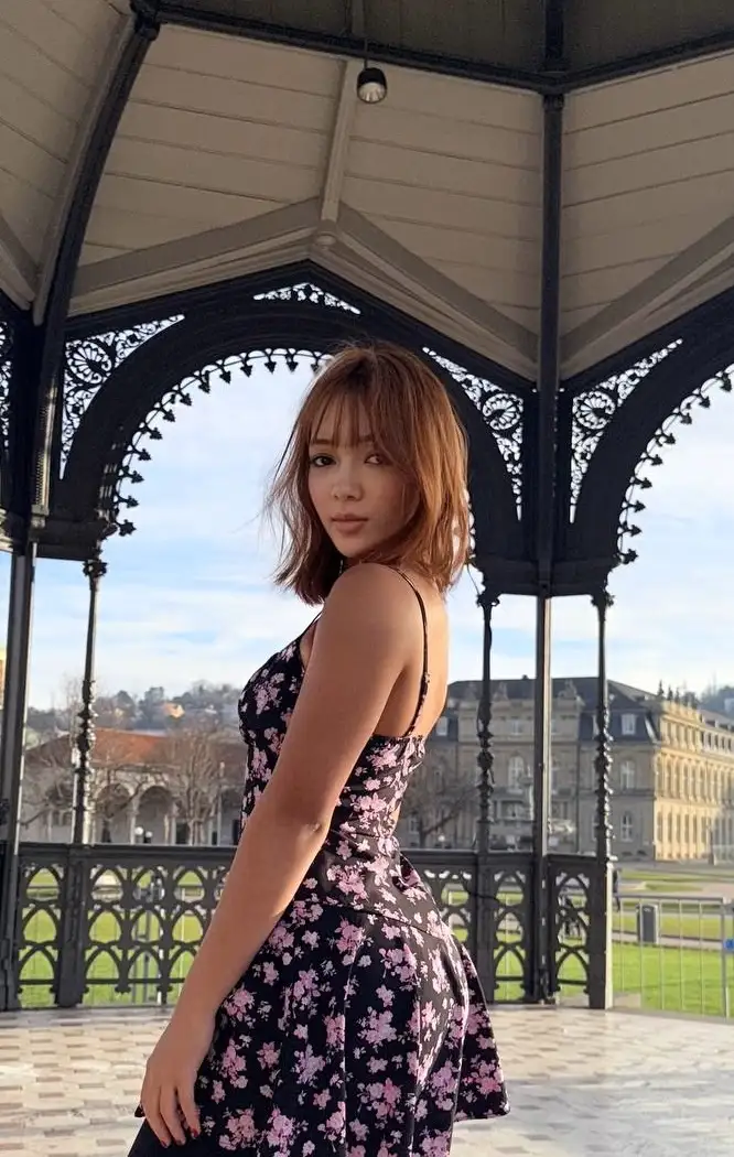 Woman in floral dress posing in an ornate black gazebo.