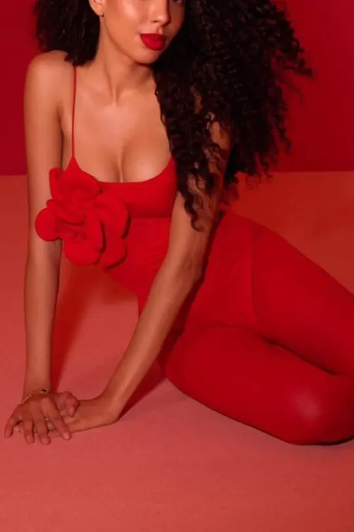 Woman in red dress posing on red background.