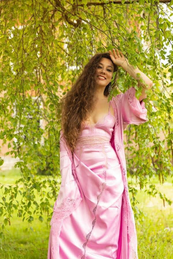 Woman in pink gown amidst greenery background
