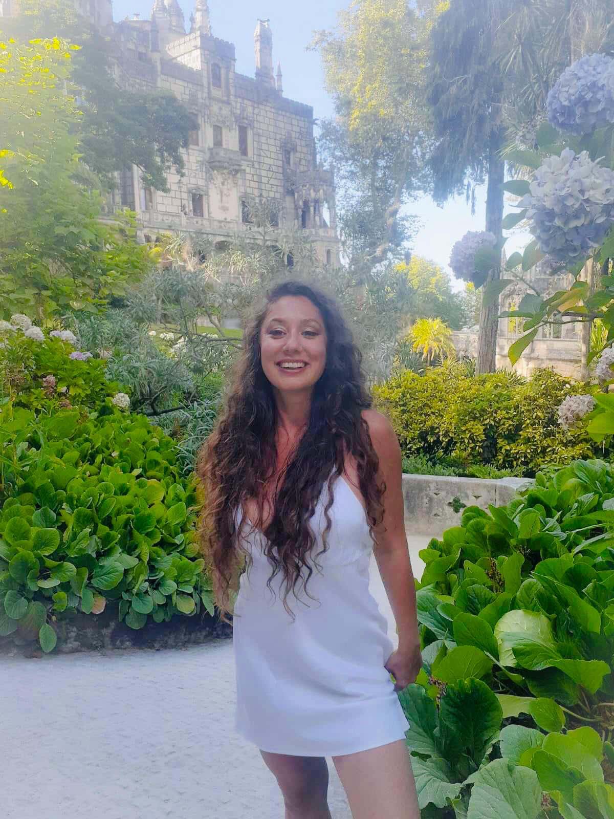 Woman in white dress in garden with castle backdrop