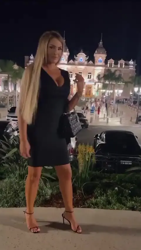 Woman in black dress outside illuminated building at night