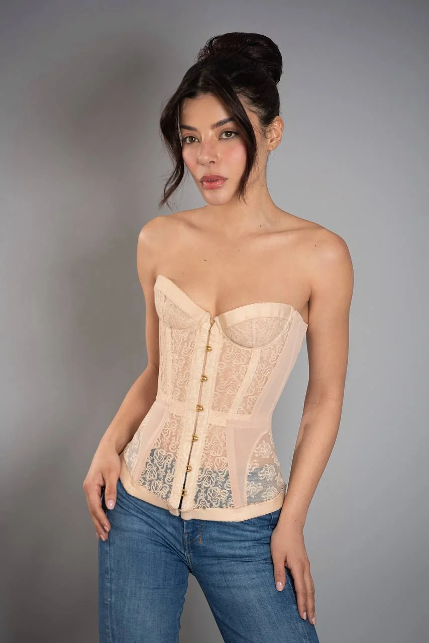 Woman posing in a peach lace corset and blue jeans