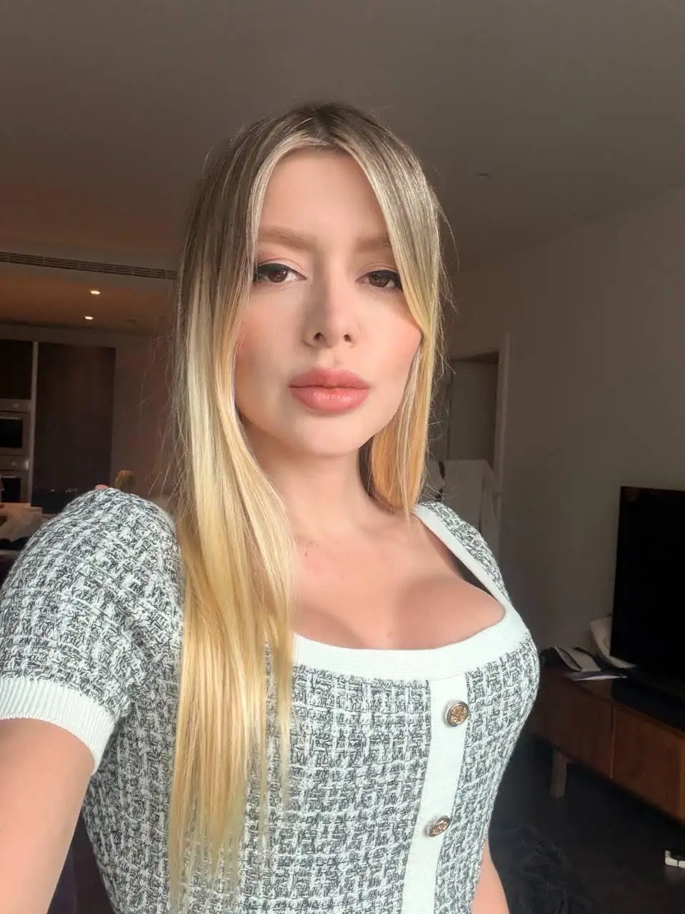 Blonde woman wearing a grey and white patterned top.