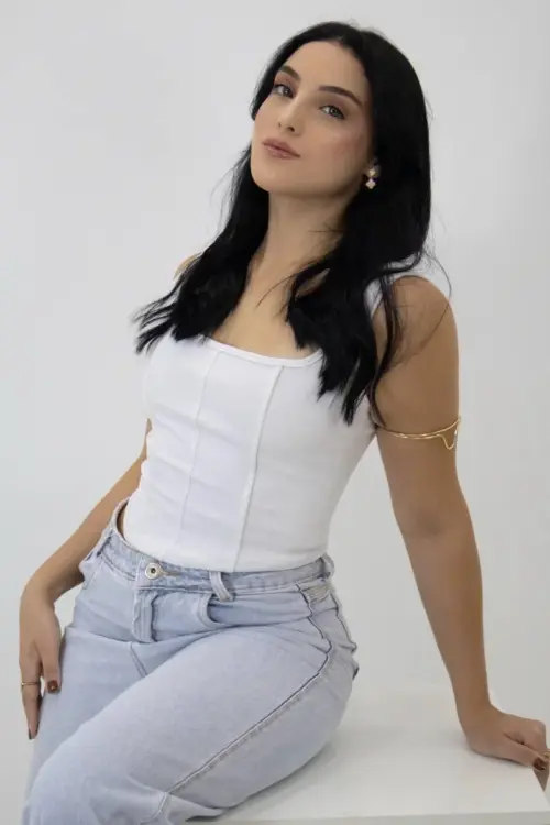 Woman posing in a white corset top and blue jeans