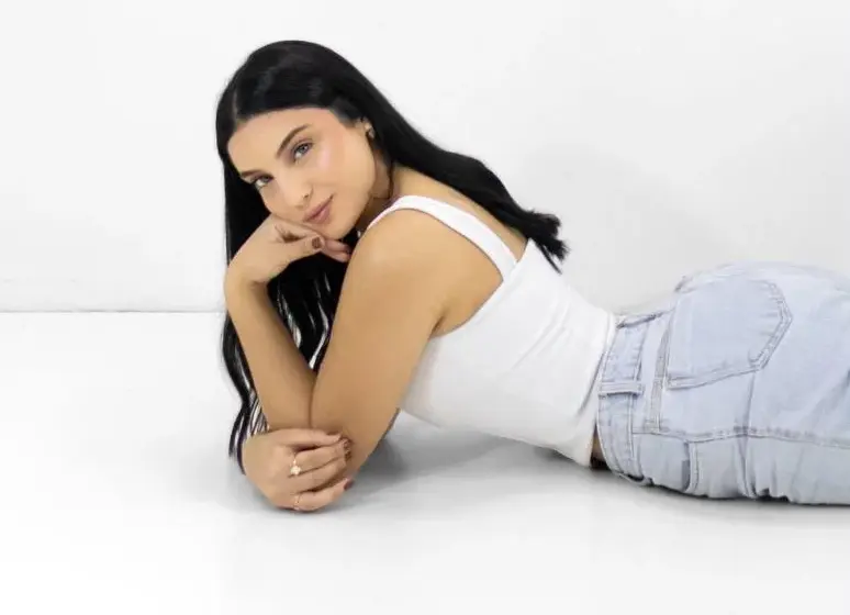 Woman with long black hair lying on a white surface