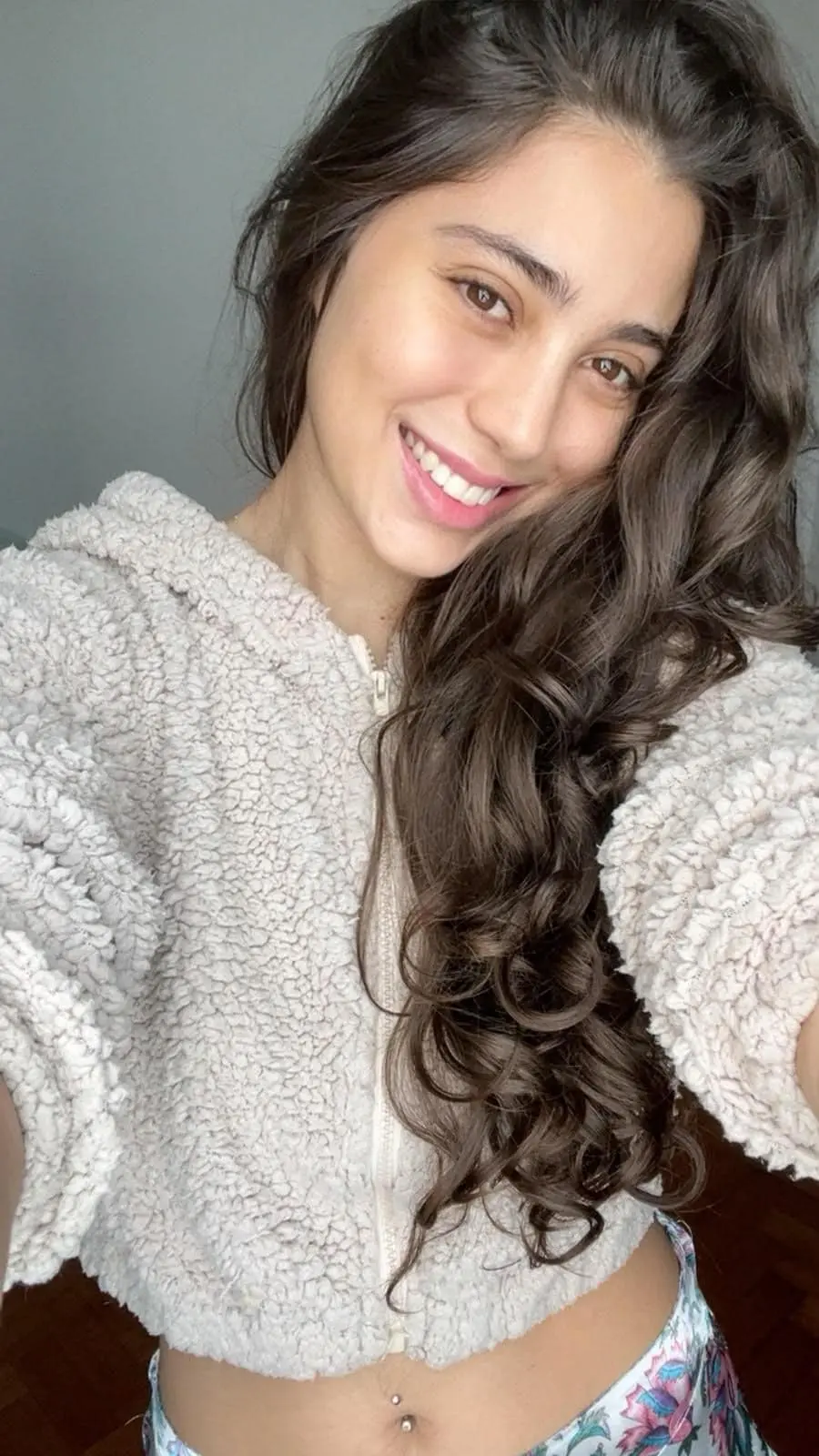 A woman with long curly hair wearing a fluffy hoodie.