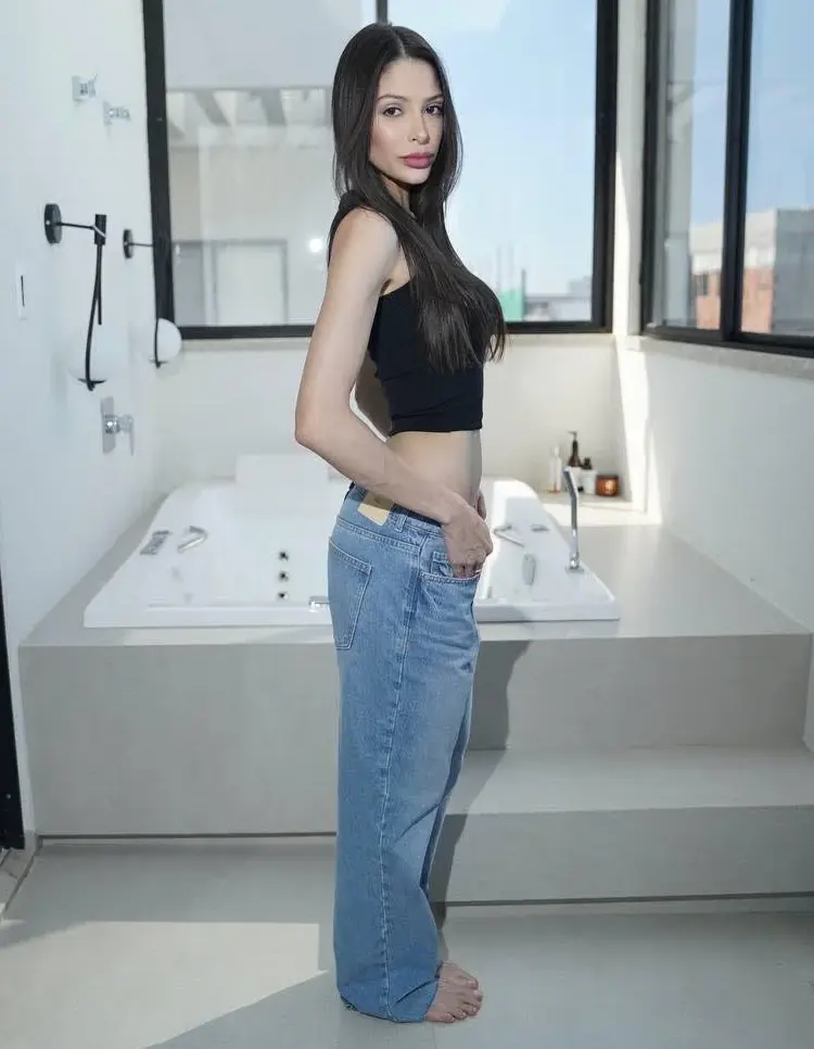 Woman in black crop top and blue jeans in bathroom