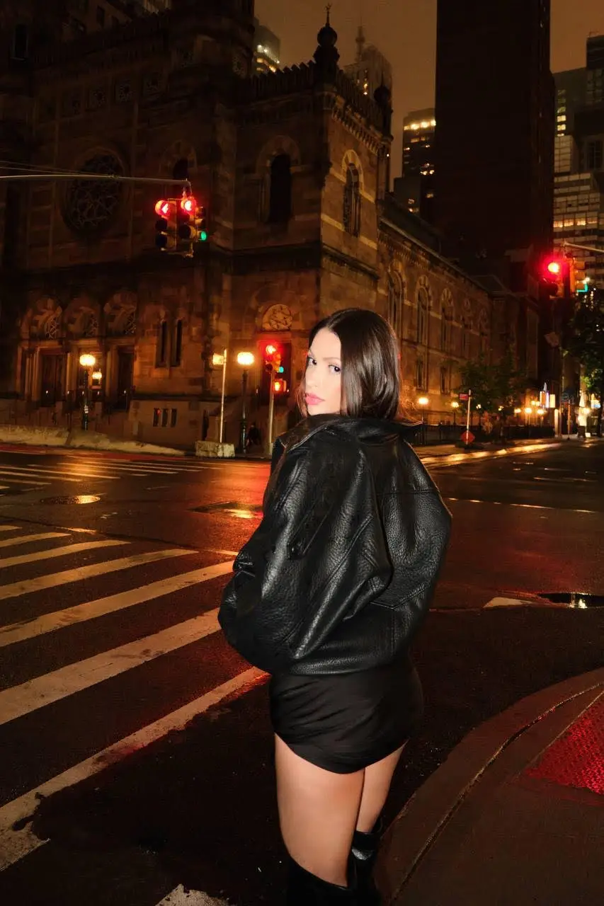 A woman in a leather jacket on a city street.