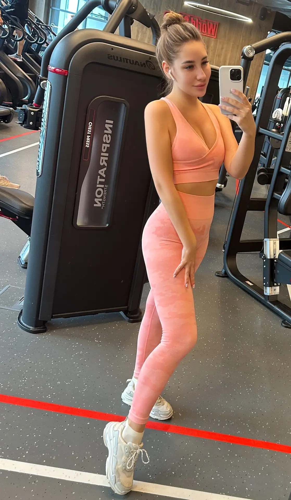 Woman in pink activewear taking a selfie in the gym.