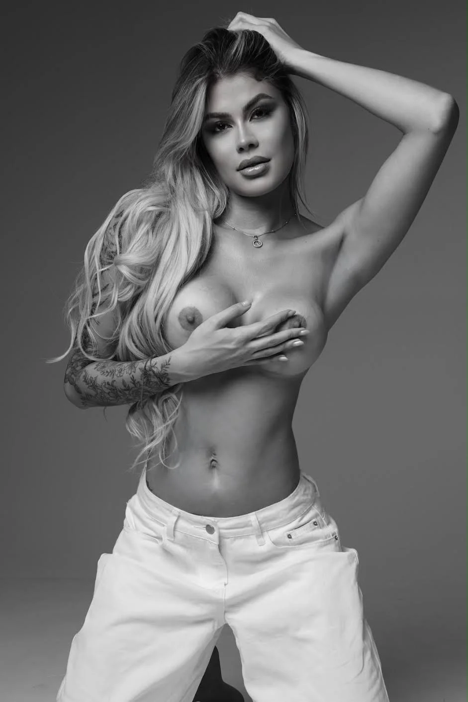 Black and white portrait of a topless woman posing.
