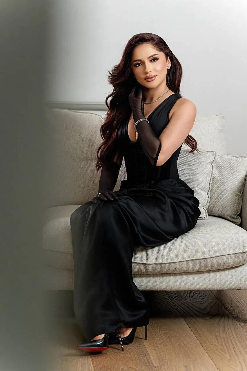 Woman in elegant black dress sitting on a cream sofa