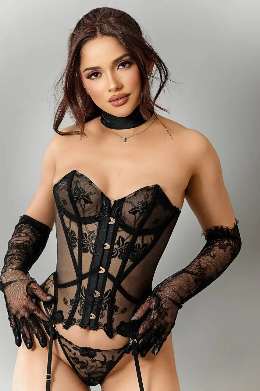 A woman posing in a black lace corset and gloves.