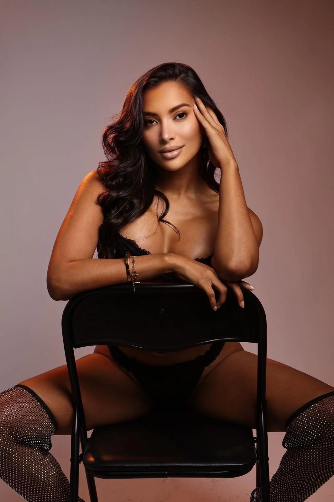 Woman in black lace lingerie sitting backwards on a chair.