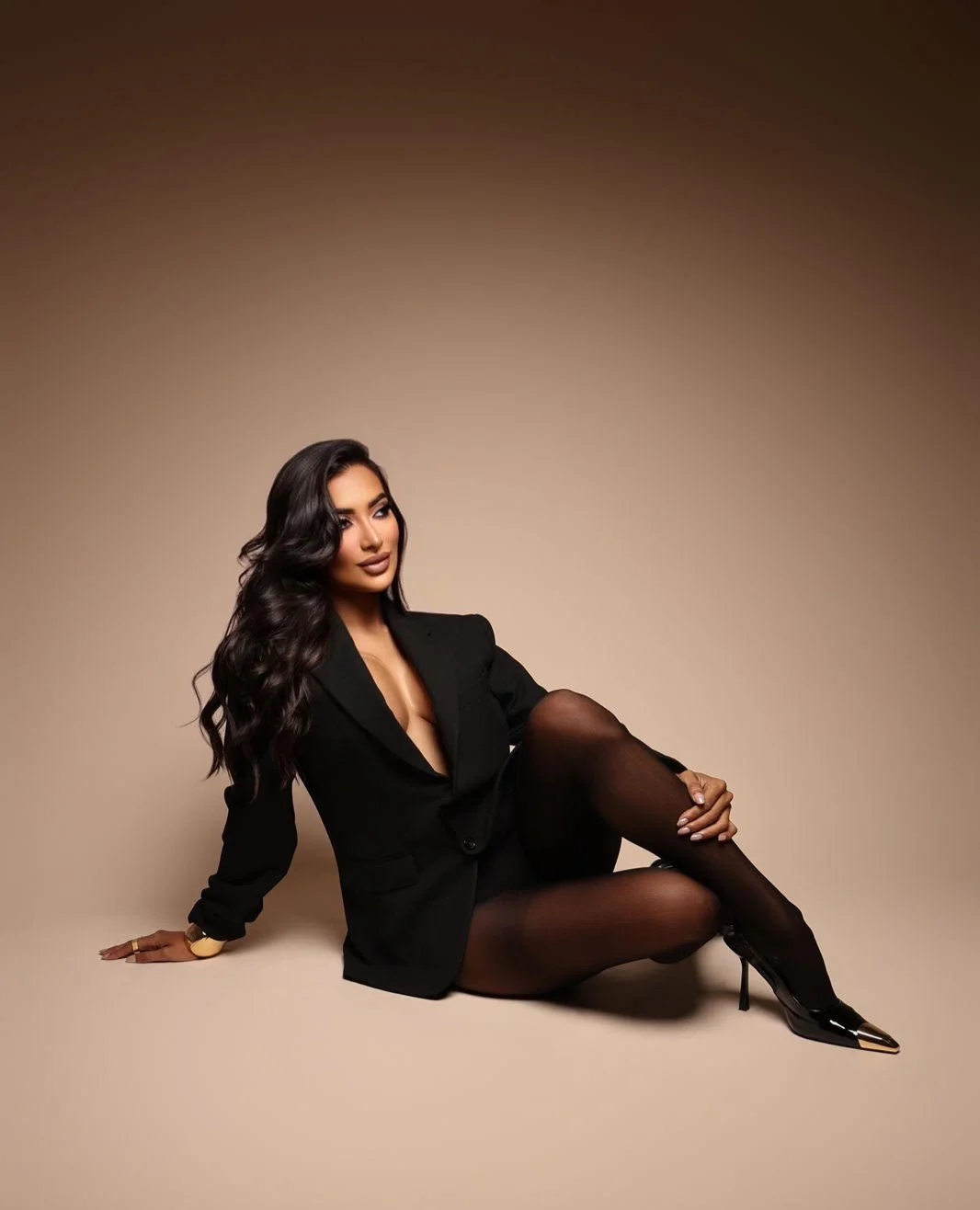 Woman in a black blazer and tights posing on floor