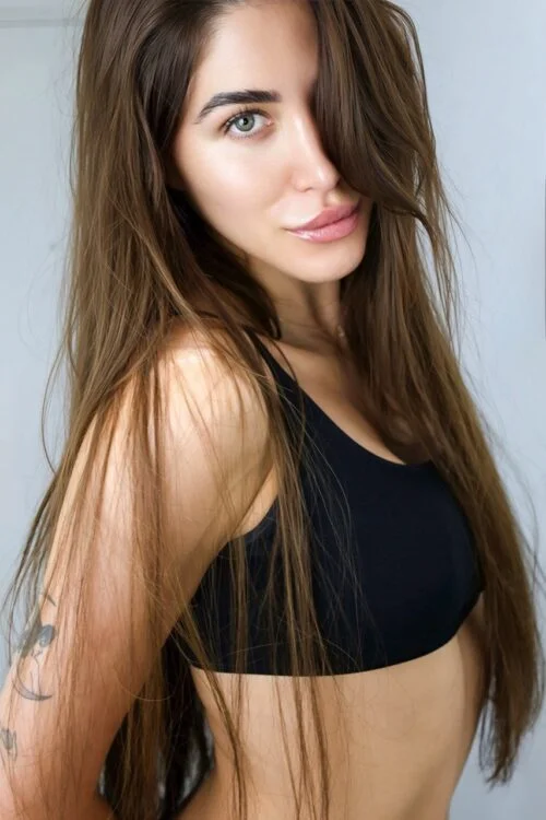 Woman with long brown hair wearing a black sports bra