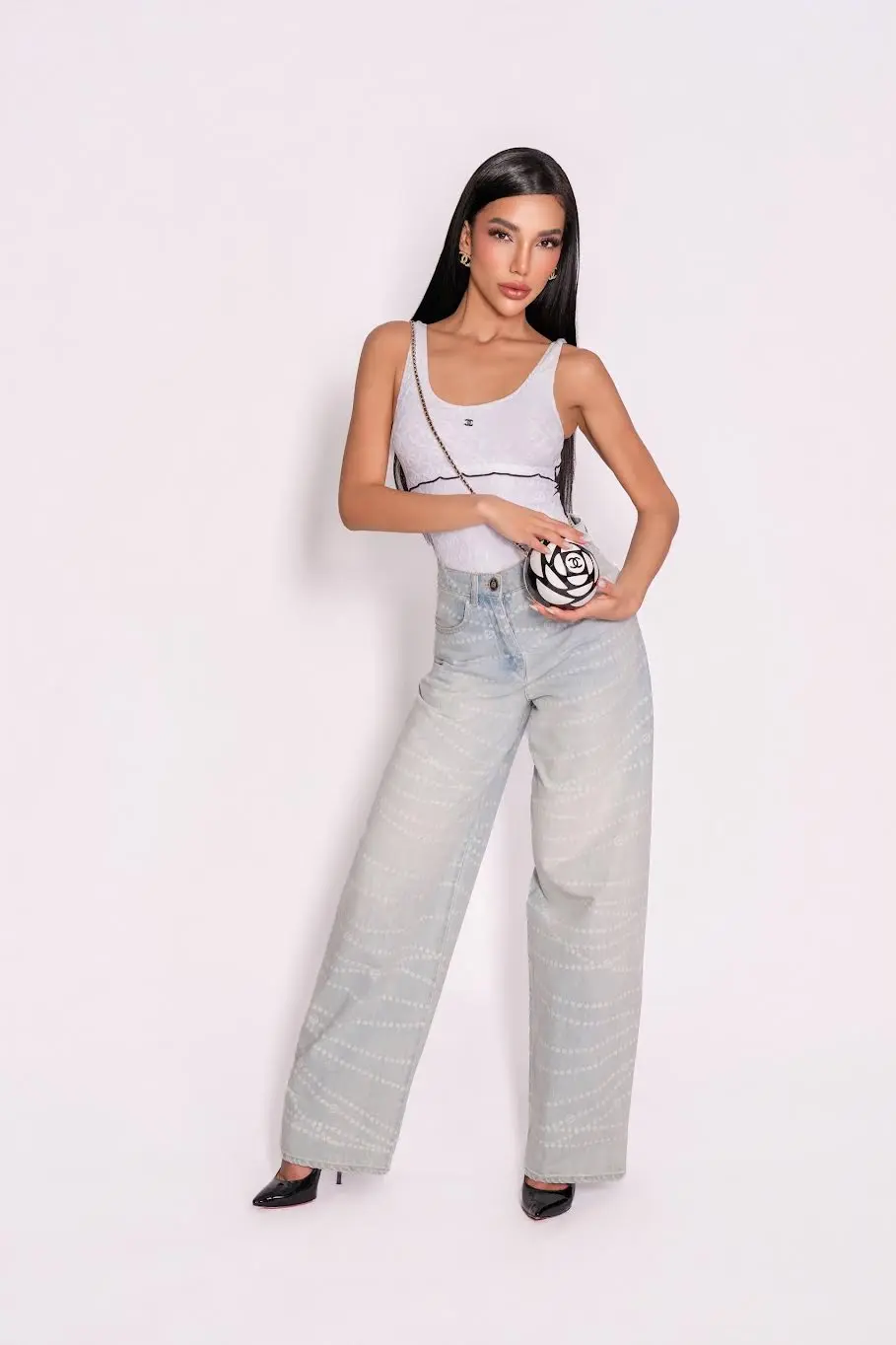 A woman posing in a white top and patterned jeans.