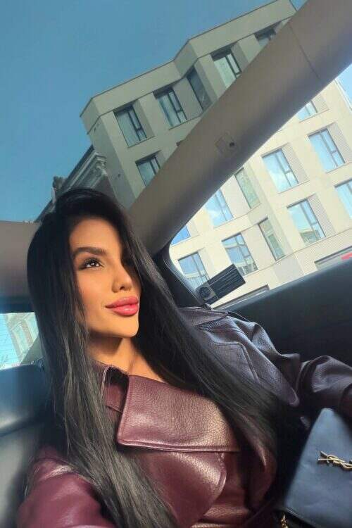 Woman in burgundy leather jacket sitting inside a car.