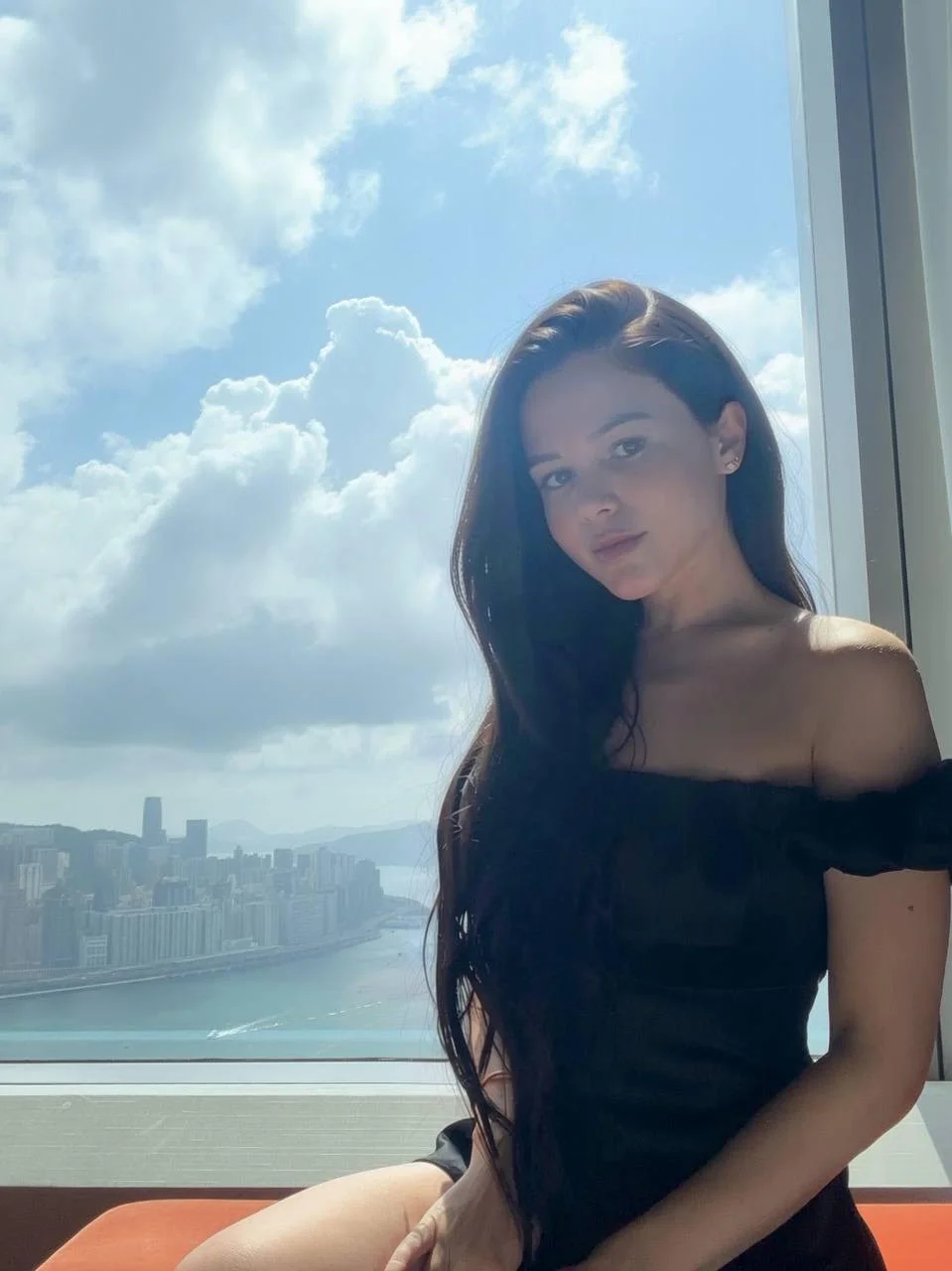 Woman in black dress by a window with harbour view
