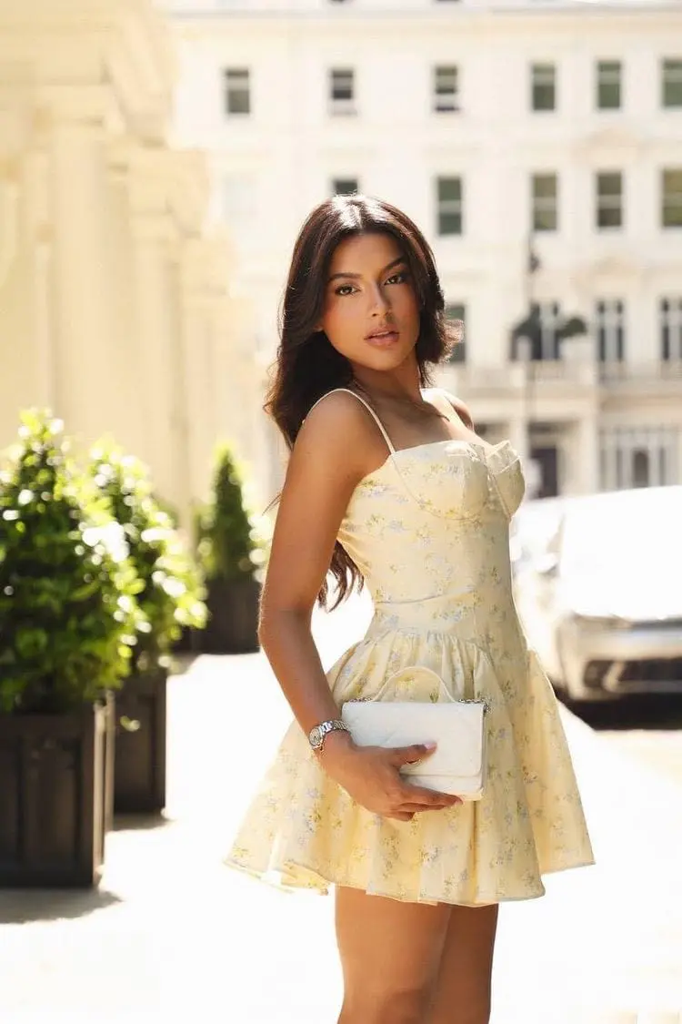 meara Woman in a yellow floral dress posing outdoors.
