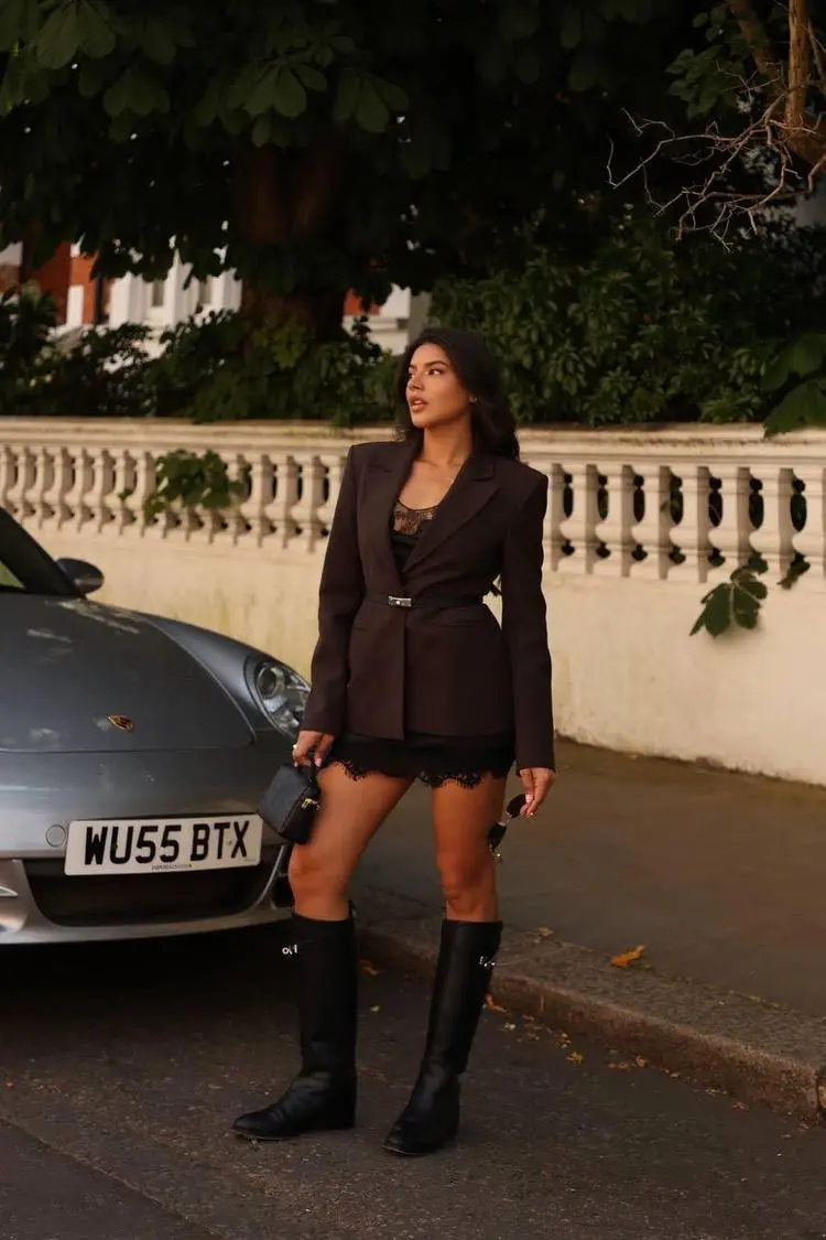 Woman in a brown blazer and black knee-high boots.