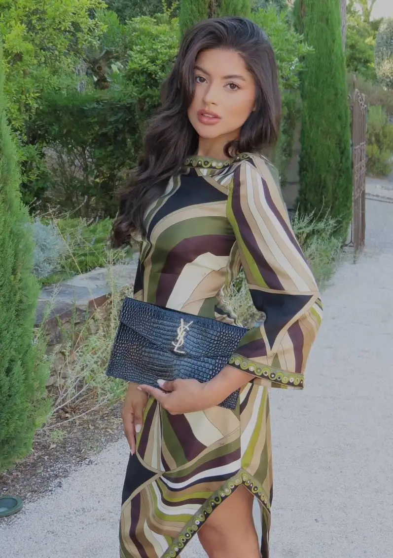 Woman in patterned dress holding a black YSL clutch