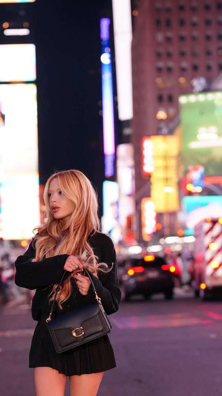 Stylish blonde woman in Times Square, New York at night.