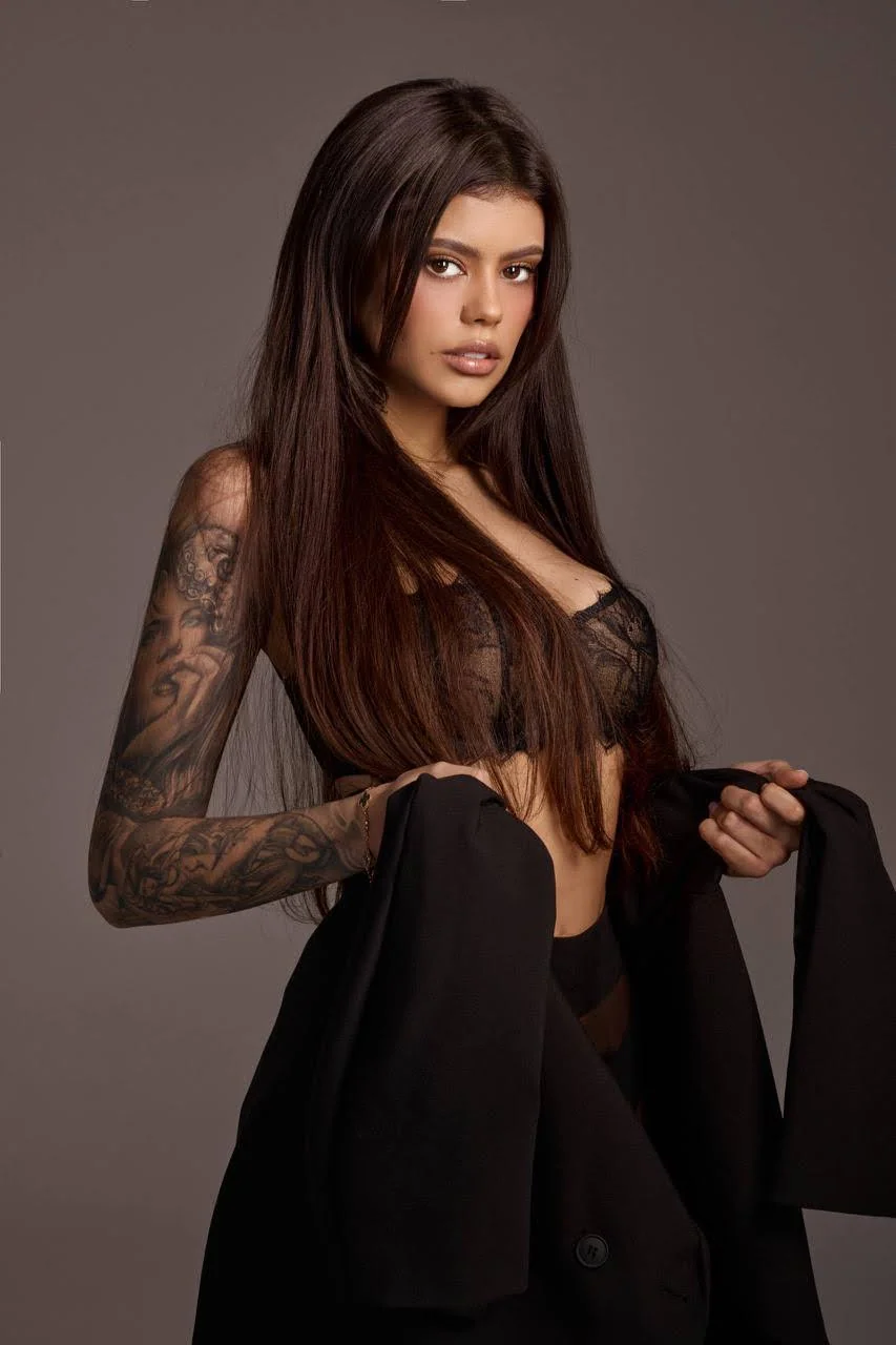 Portrait of a tattooed woman with long dark hair.