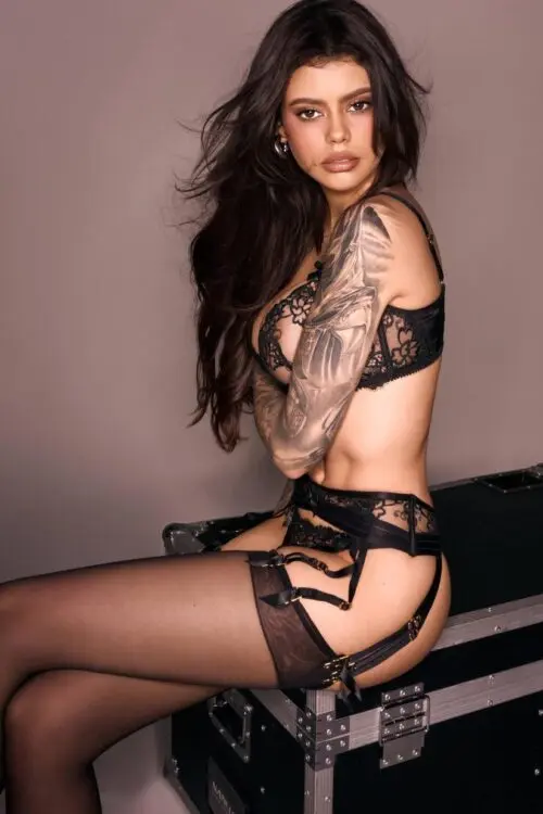 Woman in black lace lingerie with a sleeve tattoo.