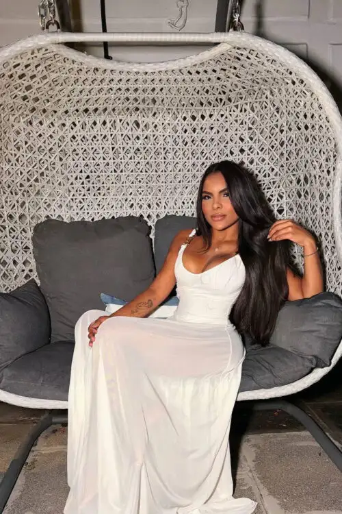 Woman in a white dress sitting in a wicker chair.