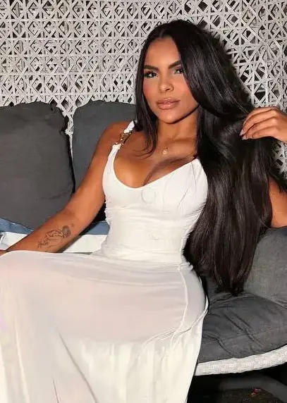 Woman in a white dress sitting in a wicker chair.